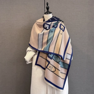 Winter scarf with vintage belt buckle pattern and tassels shown on a white coat