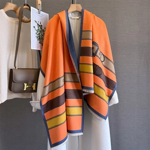 Detail of a thick orange pashmina featuring vintage leather belt prints and frayed edges