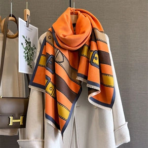 Chic orange scarf with belt buckle pattern and fringe, paired with white wool coat