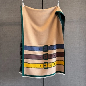 Detail of winter thick shawl featuring horizontal belt buckle patterns and white tassels