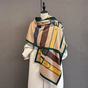 Close-up of winter scarf showing jacquard belt buckle pattern and soft fringe trim