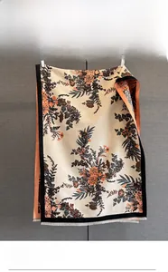 Close-up of vintage floral jacquard pattern and fringe detail on beige cashmere-like scarf