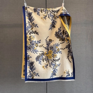 Close-up of floral cashmere feel scarf featuring deep blue botanical patterns and fringe trim