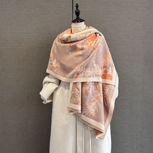 Close-up of floral cashmere feel scarf with fringe detail and orange botanical patterns