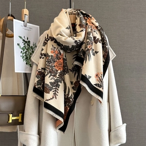 Vintage floral cashmere scarf with orange blossoms and fringe on a white coat