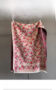 Detail of rose jacquard scarf featuring intricate floral patterns and white fringe edge