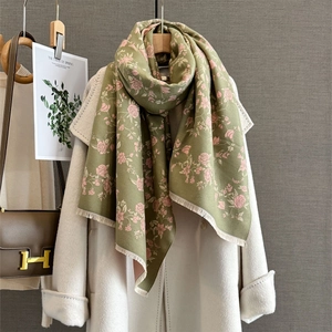 Detail view of olive green rose print scarf with fine fringe on a beige wool coat