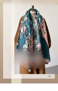 Detail of teal winter scarf with pink floral prints and fringe trim on a model