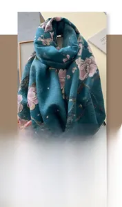 Detail of dark teal cashmere-like scarf with pink floral patterns and soft tassels