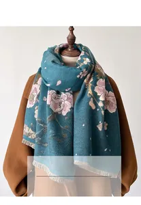 Detail of dark teal winter scarf with pink floral patterns and white fringe on a coat