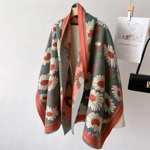 Winter pashmina shawl with daisy patterns and fringe edges on a wooden hanger
