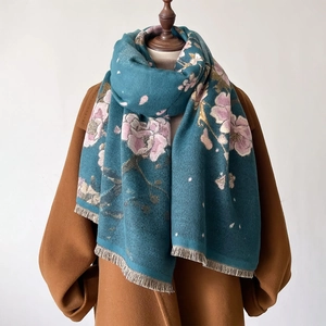 Winter teal scarf with pink floral patterns and fringe edges over a brown wool coat