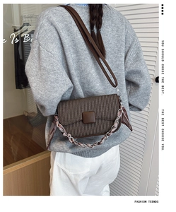 Detail of dark brown woven crossbody bag with silk scarf chain strap on a model