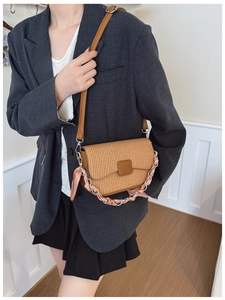 Close-up of woven straw crossbody bag with silk scarf chain strap on a model