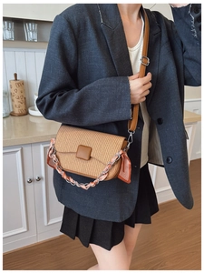 Detail of woven straw crossbody bag with brown leather flap and silk scarf chain handle