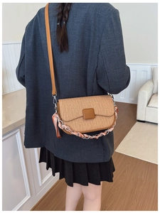 Detail of woven texture shoulder bag with leather flap and silk scarf chain handle