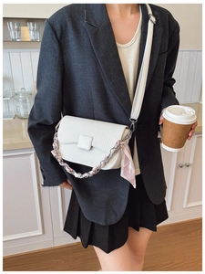 Detail of white textured crossbody bag with decorative silk scarf chain strap and long strap