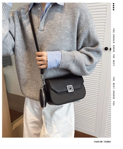 Detail of black leather crossbody bag with metal lock and round pouch attachment
