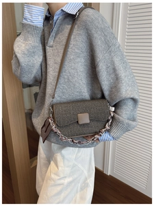 Detail of dark brown woven shoulder bag with chain strap and scarf wrap on female model