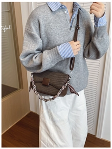 Detail of dark brown textured crossbody bag with decorative chain and silk scarf handle