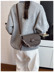 Detailed view of brown woven texture shoulder bag with decorative chain and silk scarf