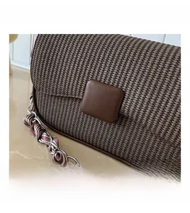 Detail showing deep brown woven texture and chain strap with silk scarf decoration