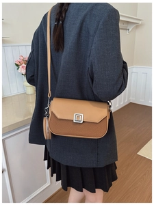 Detail of tan leather crossbody bag with woven texture and small coin purse attachment