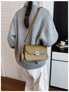 Detailed view of an olive green crossbody bag featuring a textured weave and round coin purse