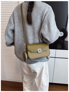 Olive green crossbody bag with textured weaving and a small round coin purse charm