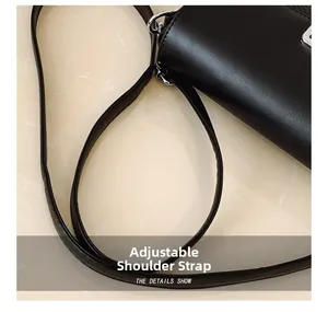 Detail of black leather bag with adjustable strap and silver metal buckle hardware