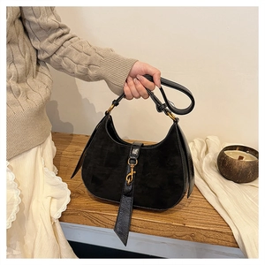 Detail of black faux suede crescent bag with gold metal buckle and leather trim