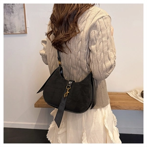 Close-up of black suede moon bag with golden metal buckle and leather drawstring detail