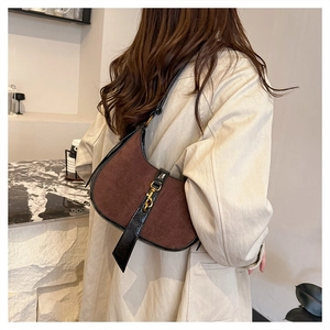 Close-up of retro suede underarm bag with black crocodile texture leather details