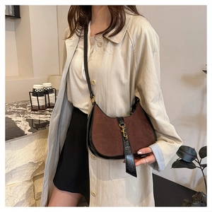 Detail of vintage suede crescent bag with gold piston lock shown in minimalist setting