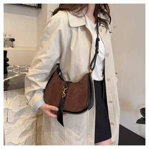 Close-up of vintage crescent shoulder bag with brown suede and black patent leather trim