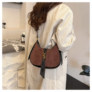 Detail of crescent shoulder bag featuring brown suede and black leather with gold piston clasp
