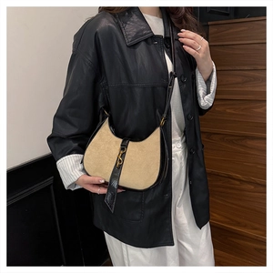 Detail of beige hobo bag with black leather trim and vintage gold metal lock buckle