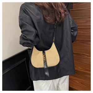 Side view of a vintage beige suede hobo bag with black leather trim and gold piston clasp