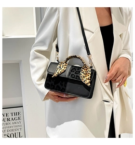Detail of crossbody bag with leopard print flap and scarf on model in white suit