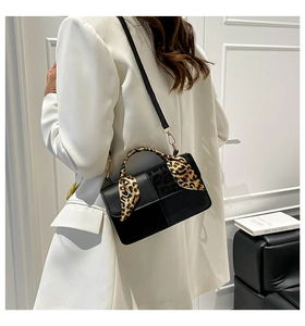 Detail of black crossbody bag with leopard print scarf handle worn with white suit