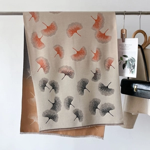 Beige poncho shawl with orange ginkgo leaf prints and fine fringe details