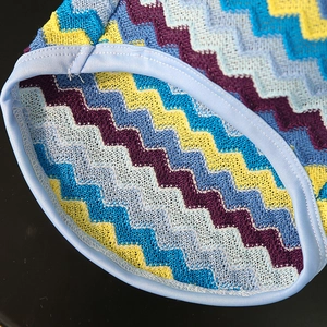 Macro shot of chevron knit pet vest featuring colorful wave patterns and soft blue piping