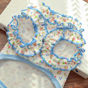 Close-up of floral pet dress with ruffled light blue edges on ribbed white fabric