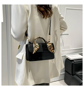 Detail of black crossbody bag with leopard print silk scarf wrapped on the handle