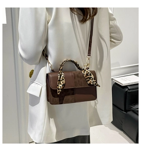 Close-up of brown textured tote bag with leopard print scarf wrap and gold hardware