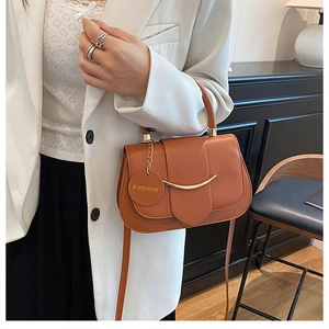 Detailansicht der braunen Ledertasche mit goldener Verzierung und modischem Anhänger