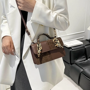 Brown textured handbag with leopard print scarf handle shown on a white blazer model