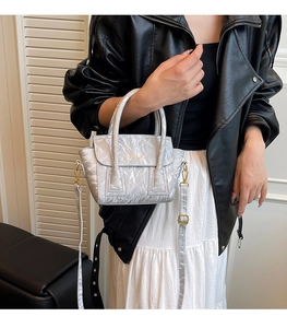 Silver metallic pleated tote bag styled with a black leather jacket and white skirt