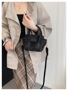 Detail of crinkled black leather handbag with gold buckle and fashion text engraving