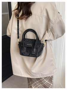 Detail of black wrinkled texture handbag with gold lettering and round metal handles